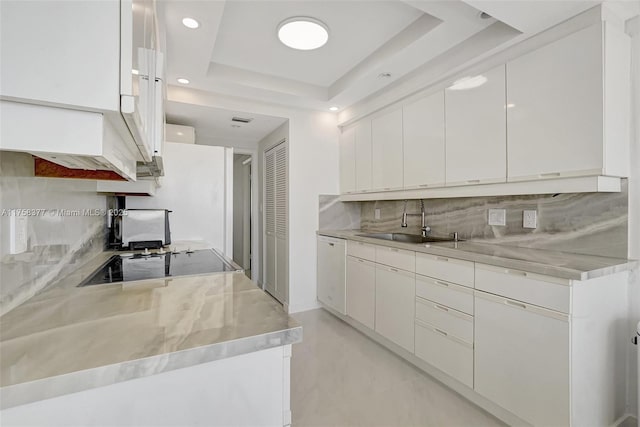 kitchen featuring a sink, backsplash, white cabinets, a raised ceiling, and dishwasher