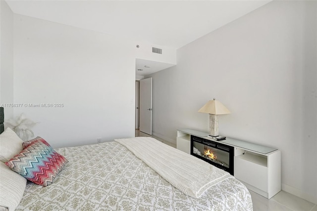 bedroom featuring visible vents and a glass covered fireplace