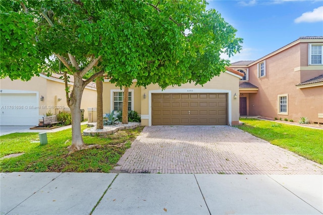 view of front facade with stucco siding, a front lawn, decorative driveway, an attached garage, and a tiled roof