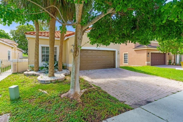 view of front facade with stucco siding, a tiled roof, decorative driveway, and fence