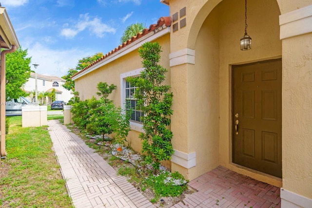 property entrance with stucco siding and a tile roof