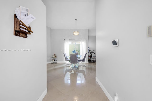 hall featuring a high ceiling and baseboards