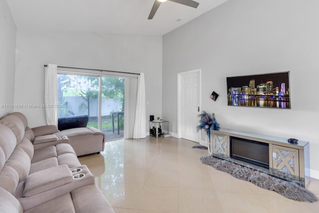 living area featuring tile patterned floors, a high ceiling, baseboards, and ceiling fan