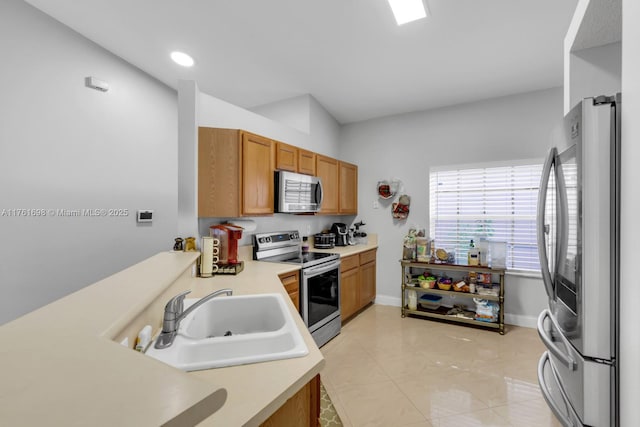 kitchen featuring light tile patterned floors, baseboards, a sink, light countertops, and appliances with stainless steel finishes