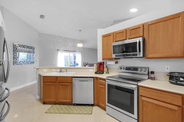 kitchen featuring appliances with stainless steel finishes, light countertops, a peninsula, and a sink