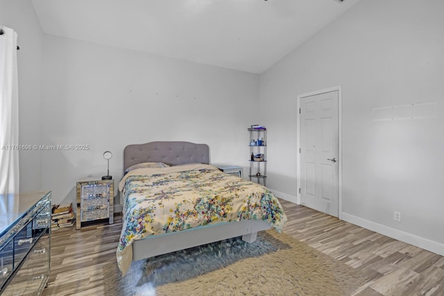 bedroom featuring lofted ceiling, wood finished floors, and baseboards