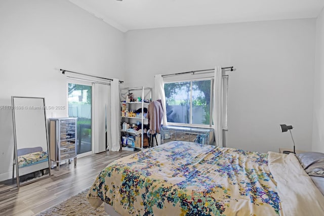 bedroom with access to exterior, multiple windows, beverage cooler, and wood finished floors