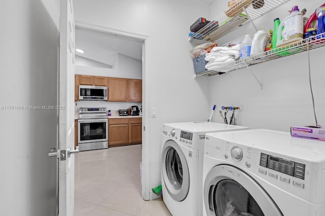 clothes washing area featuring laundry area, light tile patterned floors, and washing machine and clothes dryer