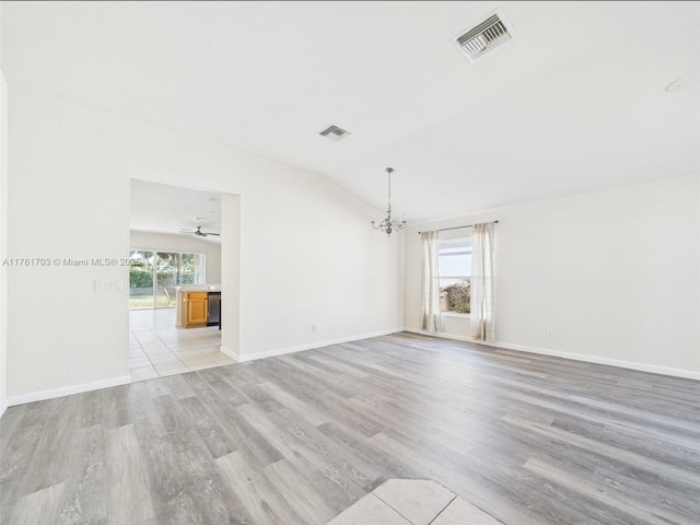 empty room featuring vaulted ceiling, a healthy amount of sunlight, and visible vents