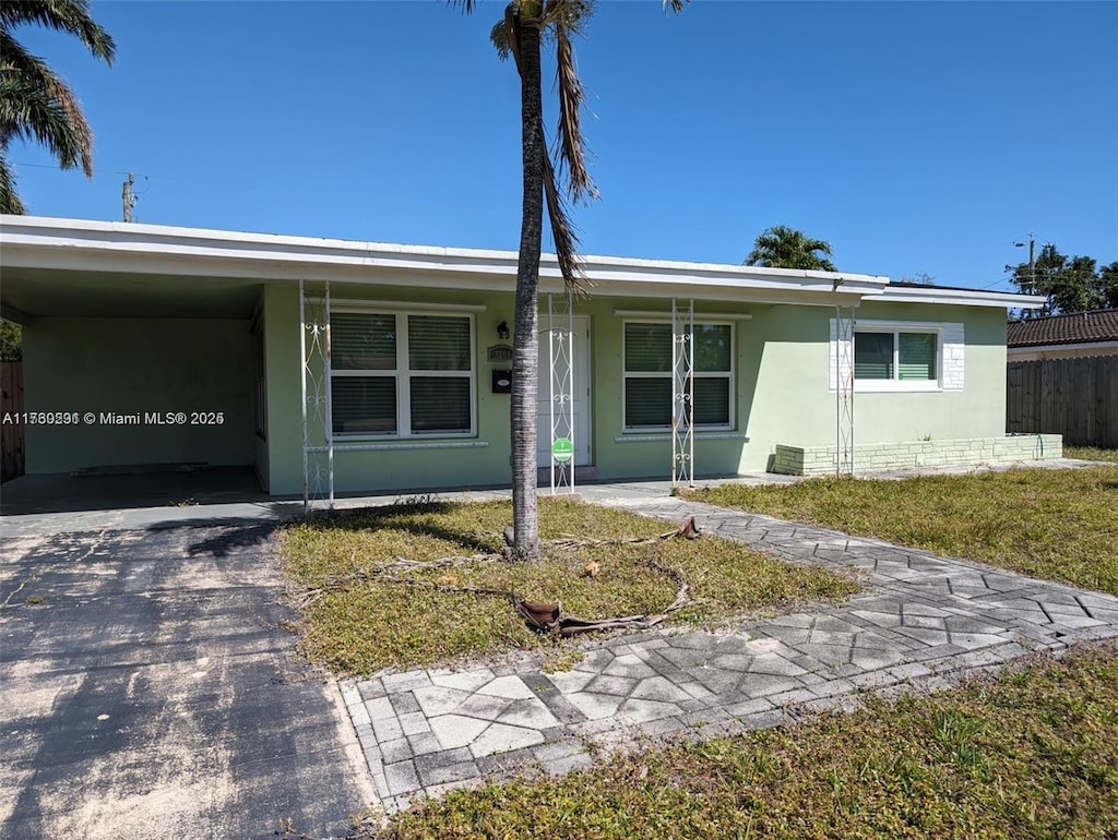 ranch-style home with stucco siding, an attached carport, driveway, and fence