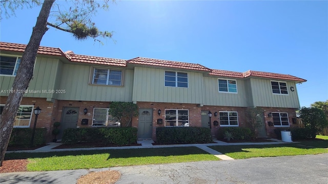 townhome / multi-family property featuring brick siding and a tile roof