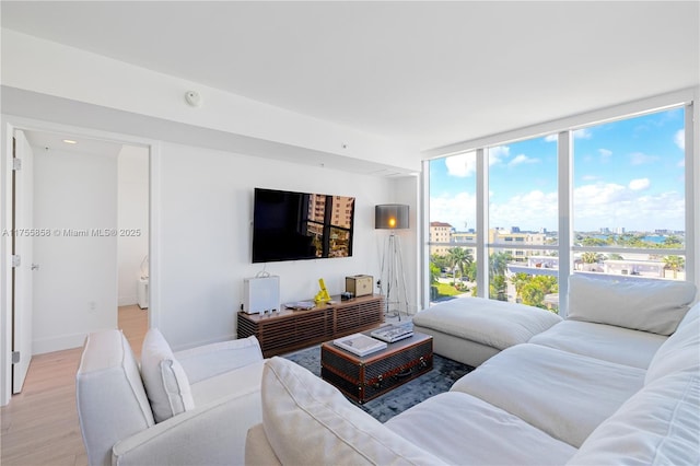 living area with a wall of windows, baseboards, and light wood-style floors