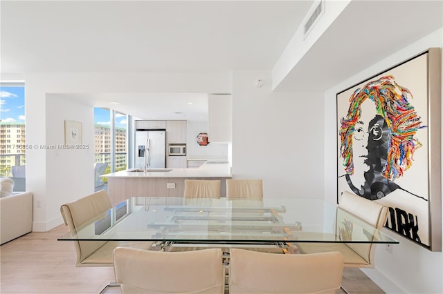 dining room with baseboards, visible vents, and light wood finished floors