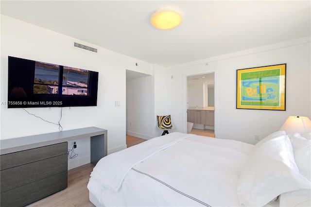 bedroom with visible vents, light wood-style flooring, ensuite bathroom, and baseboards