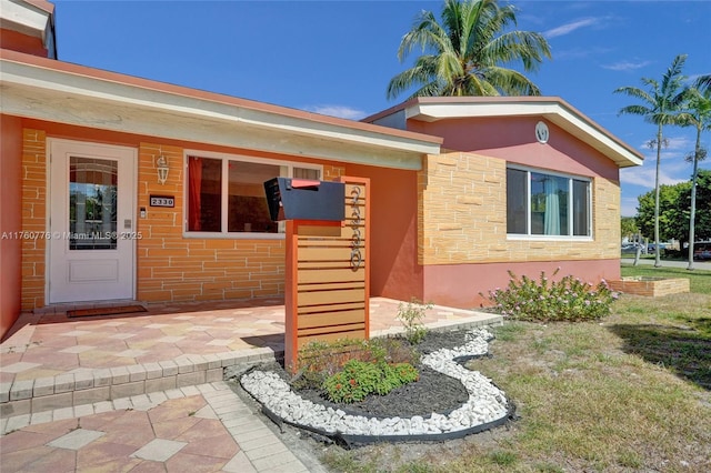 doorway to property with stucco siding and stone siding