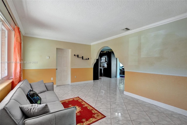 living room with visible vents, marble finish floor, ornamental molding, a textured ceiling, and arched walkways