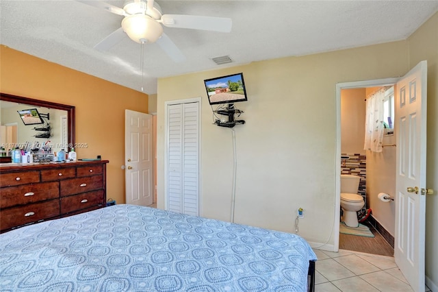 bedroom with visible vents, a textured ceiling, ensuite bath, light tile patterned floors, and baseboards