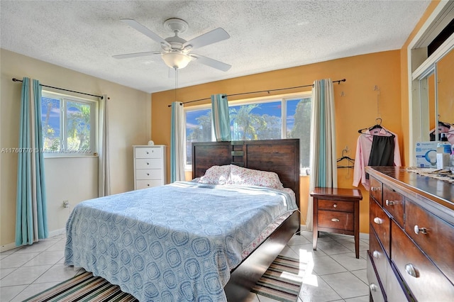 bedroom with light tile patterned floors, a ceiling fan, baseboards, and a textured ceiling