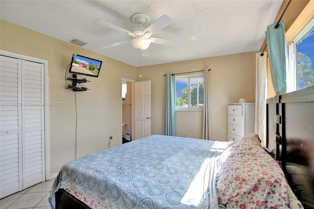 bedroom with ceiling fan, visible vents, a textured ceiling, and light tile patterned flooring