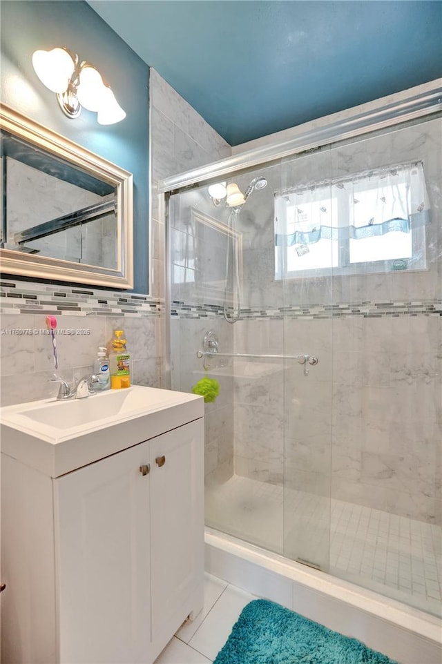 full bath with backsplash, a shower stall, tile walls, tile patterned floors, and vanity