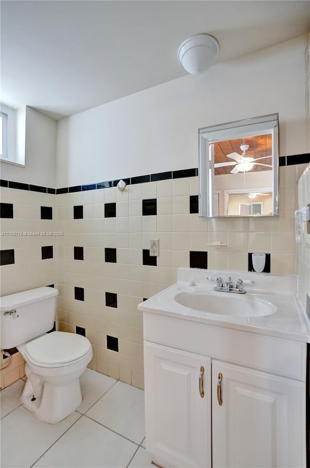 bathroom with tile patterned flooring, tile walls, toilet, and vanity