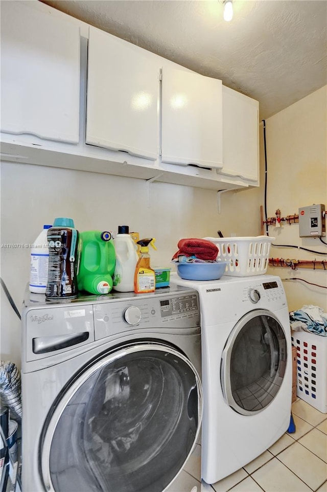 clothes washing area featuring washer and dryer, cabinet space, and light tile patterned flooring