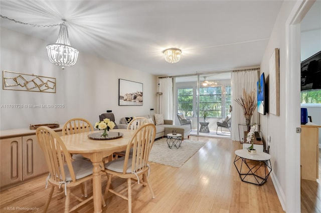 dining space with an inviting chandelier, light wood-style floors, and baseboards