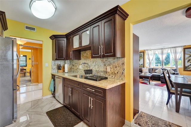 kitchen featuring visible vents, dark brown cabinets, backsplash, stainless steel appliances, and a sink