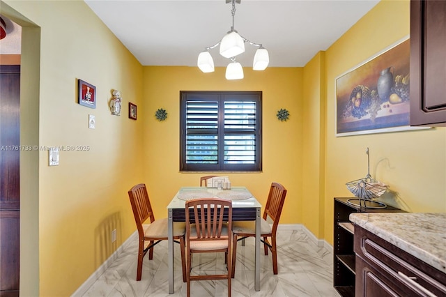 dining space featuring baseboards, marble finish floor, and a chandelier