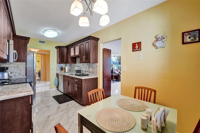 kitchen featuring dark brown cabinetry, a notable chandelier, marble finish floor, and stainless steel appliances