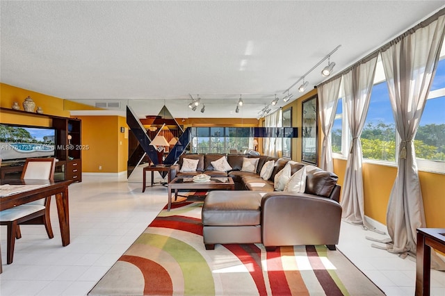 living room featuring a wealth of natural light, visible vents, and a textured ceiling