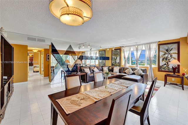 dining room featuring track lighting, light tile patterned floors, visible vents, and a textured ceiling