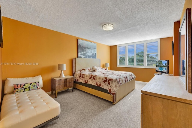 bedroom featuring light colored carpet, baseboards, and a textured ceiling