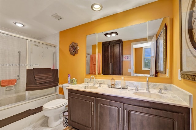 full bath featuring toilet, visible vents, combined bath / shower with glass door, and a sink