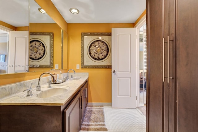 bathroom with a sink, baseboards, double vanity, and tile patterned floors