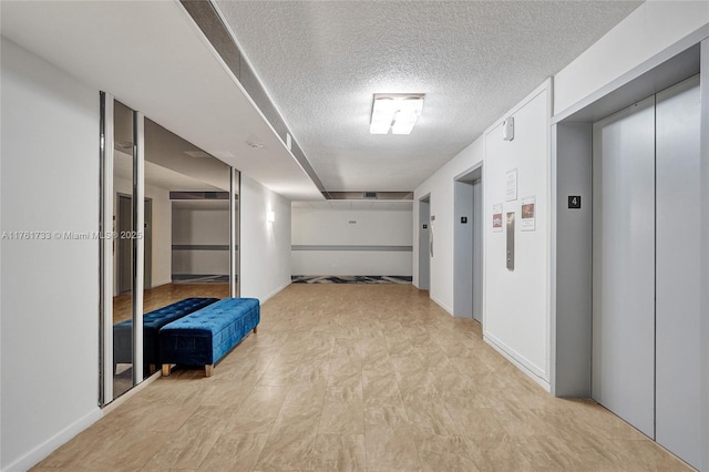 hall with elevator and a textured ceiling