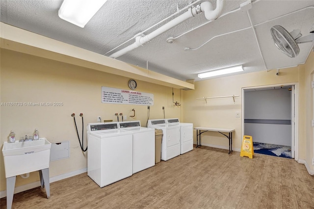 common laundry area featuring washer and dryer, a textured ceiling, and light wood finished floors