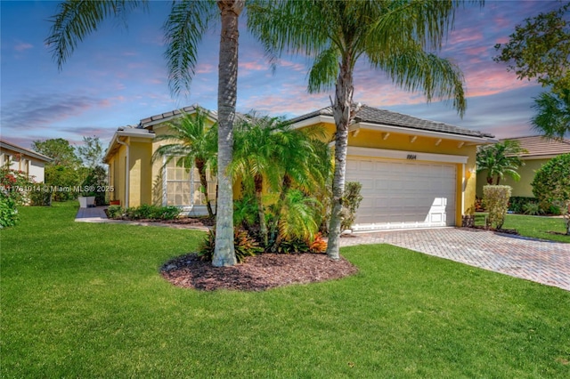 view of front facade featuring a front yard, decorative driveway, a garage, and stucco siding