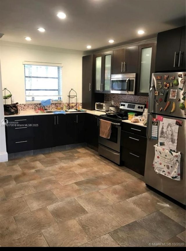 kitchen featuring recessed lighting, glass insert cabinets, appliances with stainless steel finishes, and dark cabinets