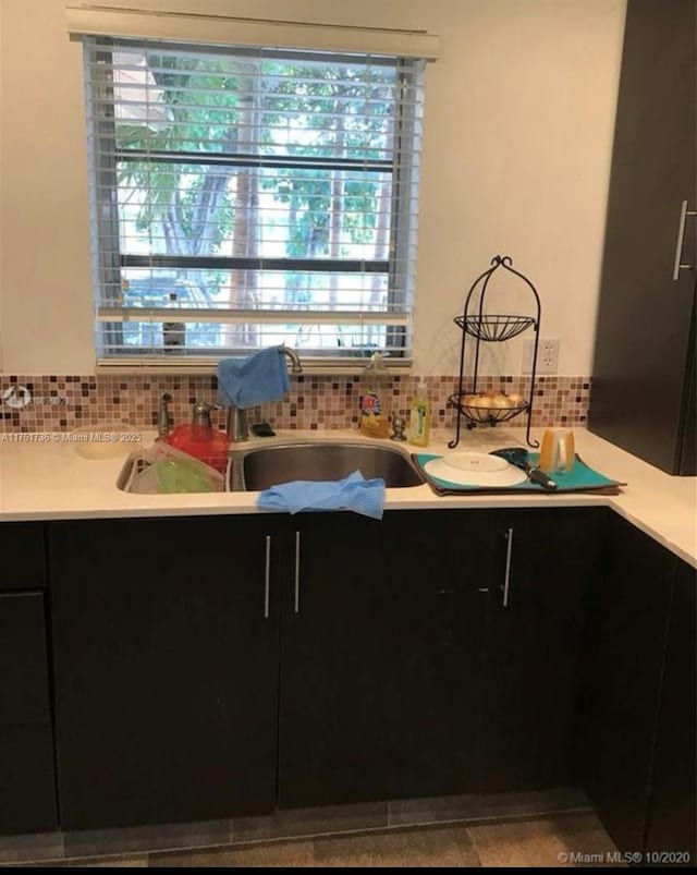 kitchen featuring tasteful backsplash, a healthy amount of sunlight, dark cabinetry, and light countertops