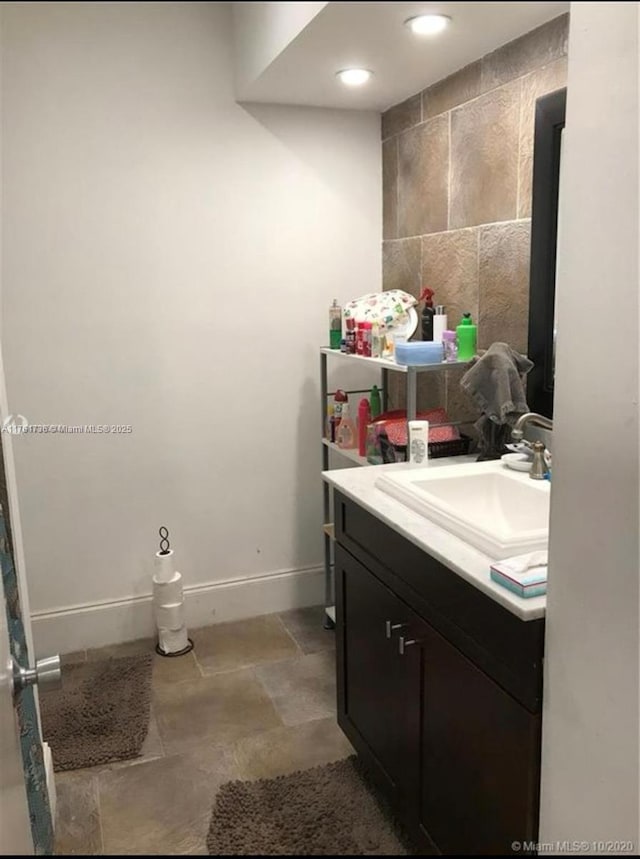 bathroom featuring recessed lighting, vanity, tile walls, and baseboards