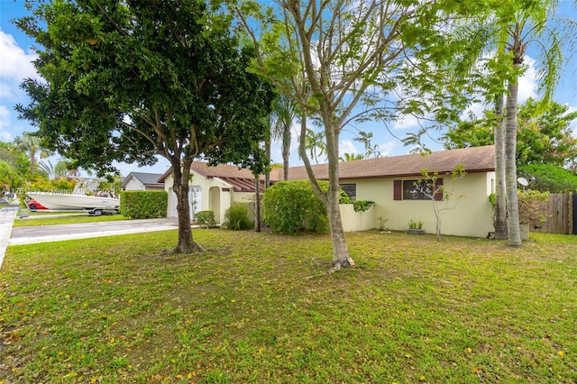 single story home featuring an attached garage, a front lawn, fence, stucco siding, and driveway