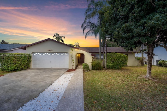 ranch-style house with a front yard, a garage, driveway, and stucco siding