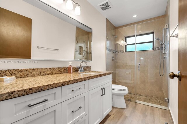 full bathroom with vanity, wood finished floors, visible vents, a stall shower, and toilet