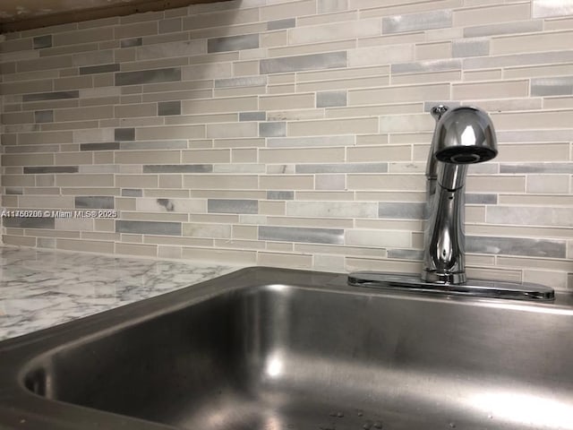 interior details featuring tasteful backsplash, light stone countertops, and a sink