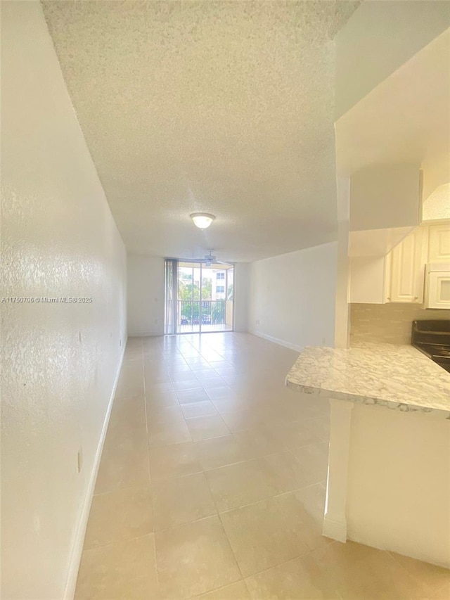 spare room with light tile patterned flooring, baseboards, and a textured ceiling