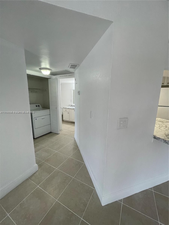 hall featuring visible vents, baseboards, washer / dryer, and tile patterned flooring