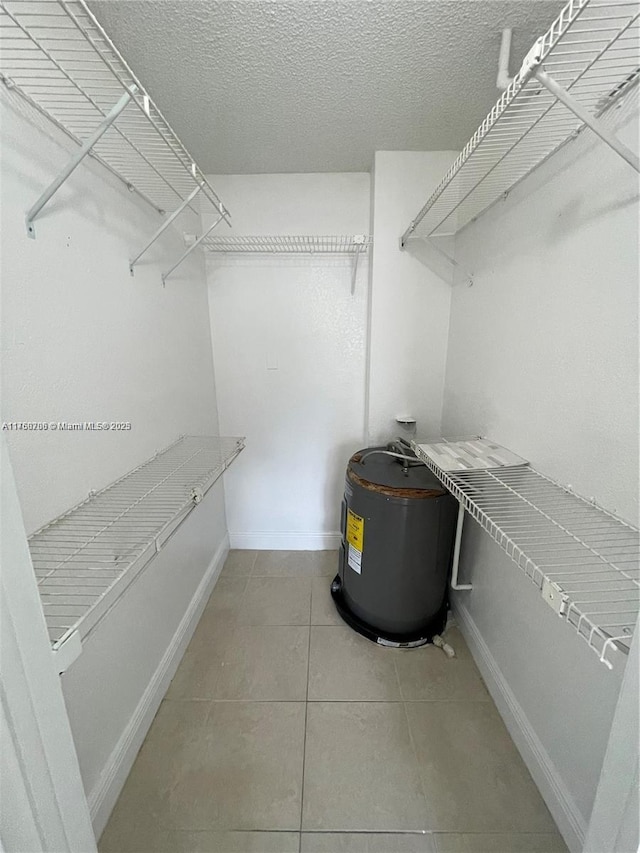 walk in closet featuring light tile patterned flooring and electric water heater