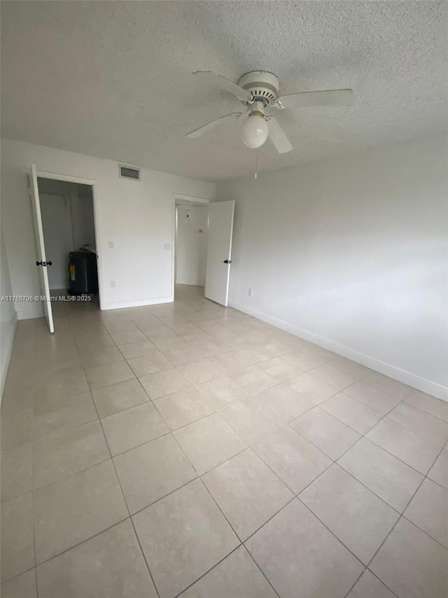 spare room featuring visible vents, baseboards, a textured ceiling, and ceiling fan