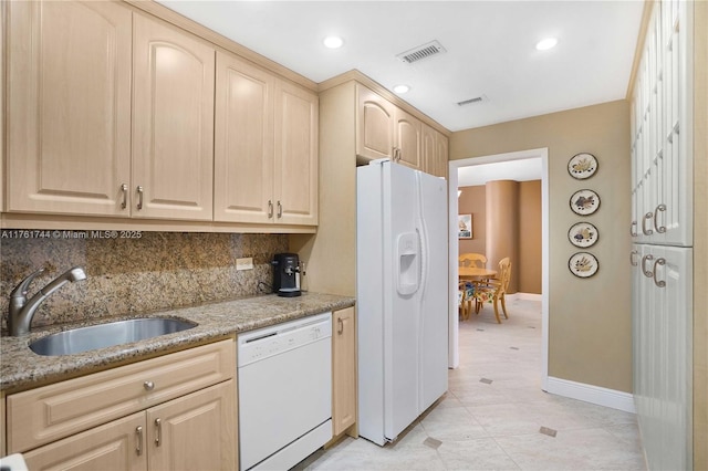 kitchen with light brown cabinets, visible vents, white appliances, and a sink